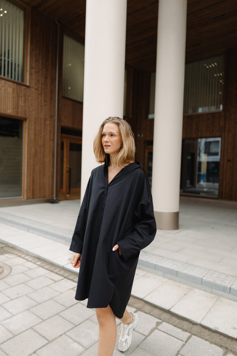 Woman in a black coat standing in front of a building with columns