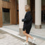 Woman in a black dress standing near columns in an outdoor setting
