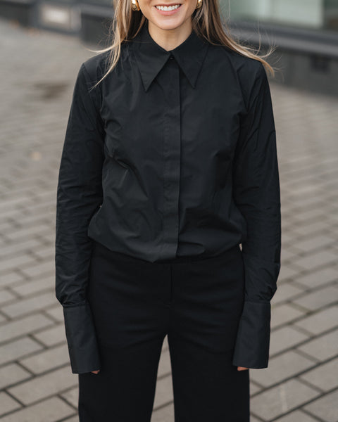 Person wearing a black outfit standing on a paved surface