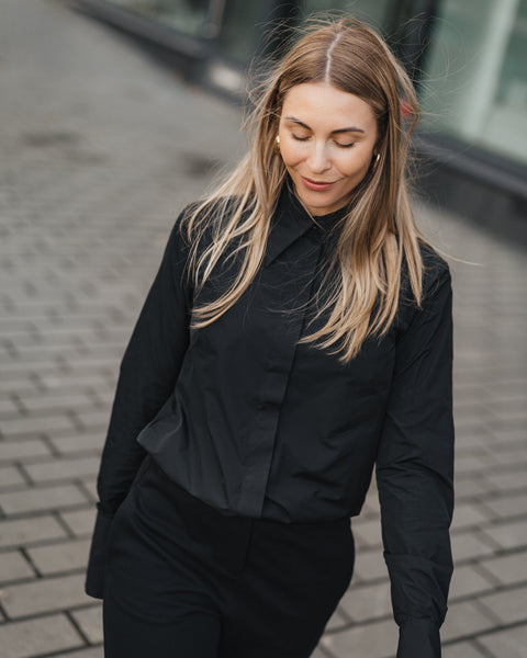 Woman in a black outfit walking on a street.